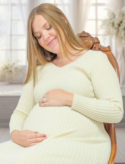 "Woman in chair with hands hold stomach looking down smiling."