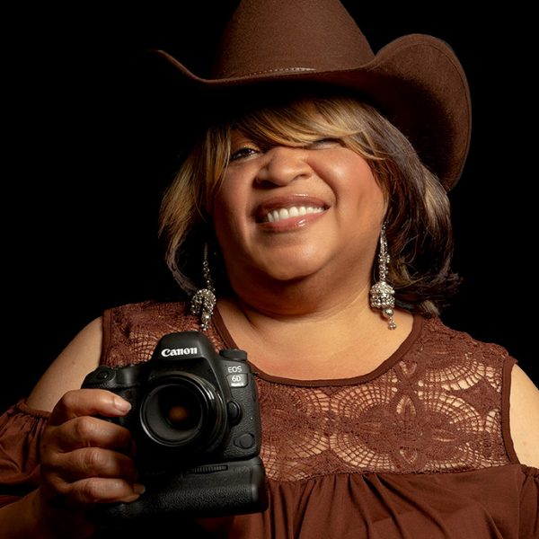 "Woman photographer in a brown hat smiling."